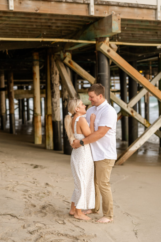 San Clemente Pier Engagement Photos with couple wearing white and tan