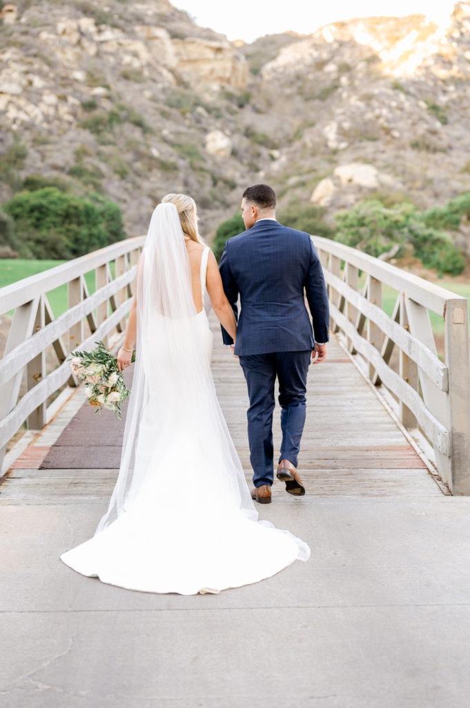Bride and groom walking away on a bridge in Laguna Beach