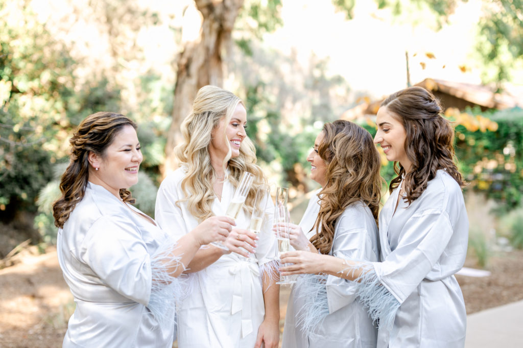 Bride with bridesmaids "cheers" their champagne flute