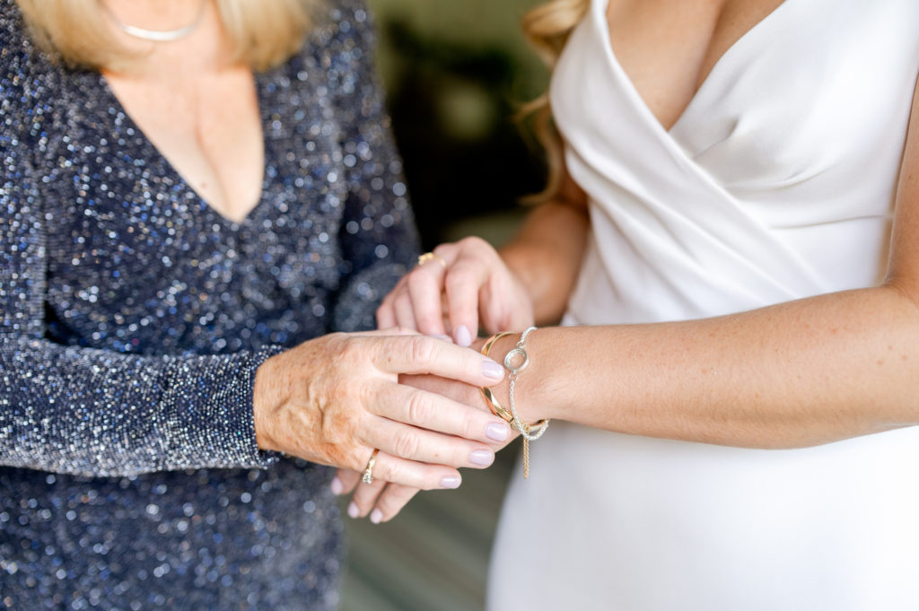 Mother of the bride putting on a irish bracelet on the bride's wrist